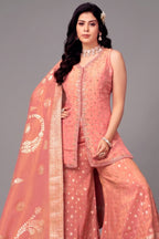 Woman wearing a traditional pink outfit with a matching dupatta on a gray background