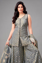 Woman wearing a traditional outfit with a gray top and skirt on a gray background